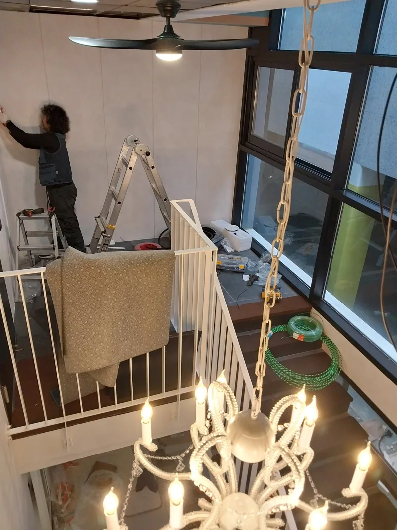 주거공간 계단과 난간 주변에서 조명 및 벽면 작업을 진행하는 모습